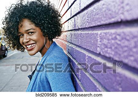 Stock Photography - Mixed race woman standing by colorful wall. Fotosearch