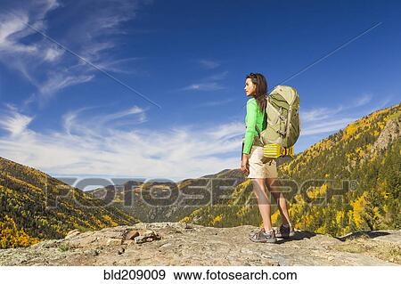 Stock Photo - Mixed race woman standing on rocky hilltop. Fotosearch