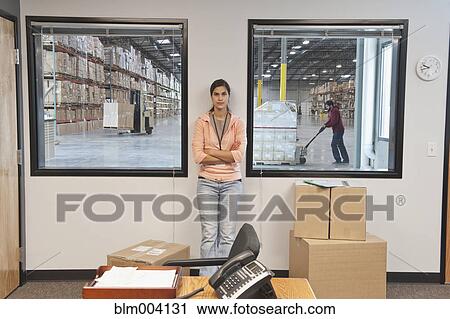 Mixed race woman standing with arms crossed in warehouse office View Large Photo Image Stock Image - Mixed race woman standing with arms crossed in warehouse office. Fotosearch
