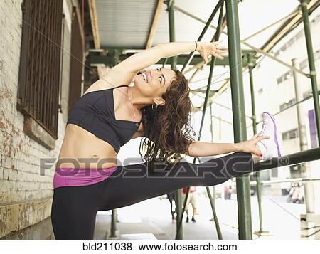 Stock Photo - Mixed race woman stretching on urban scaffolding. Fotosearch