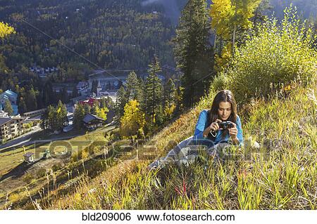 Stock Photograph - Mixed race woman taking pictures on rural hillside. Fotosearch