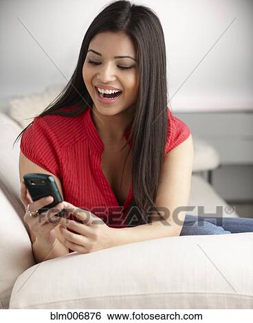 Stock Photograph - Mixed race woman text messaging on cell phone. Fotosearch