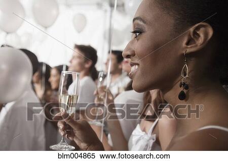 Stock Photography - Mixed race woman toasting with glass of champagne. Fotosearch