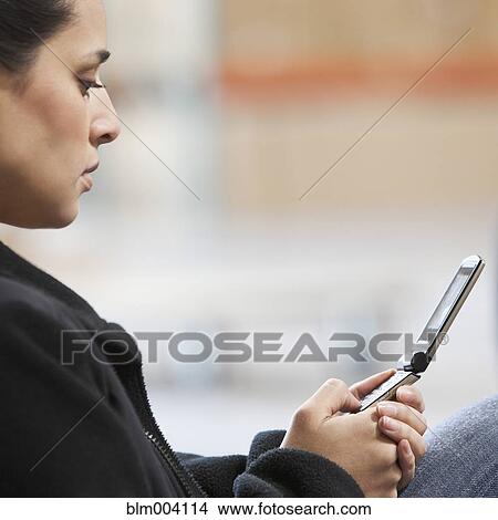 Picture - Mixed race woman using cell phone. Fotosearch