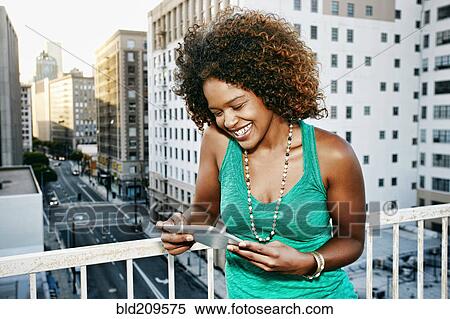 Mixed race woman using digital tablet on urban rooftop View Large Photo Image Stock Photography - Mixed race woman using digital tablet on urban rooftop. Fotosearch