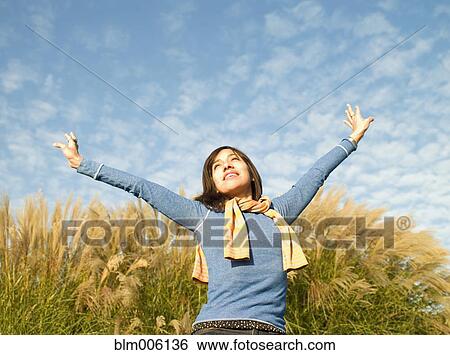 Stock Photograph - Mixed race woman with arms outstretched outdoors. Fotosearch
