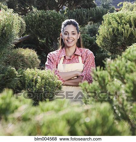Stock Photo - Mixed race woman working in garden nursery. Fotosearch