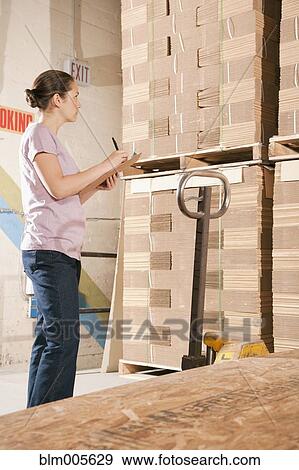 Stock Photo - Mixed race woman working in warehouse. Fotosearch