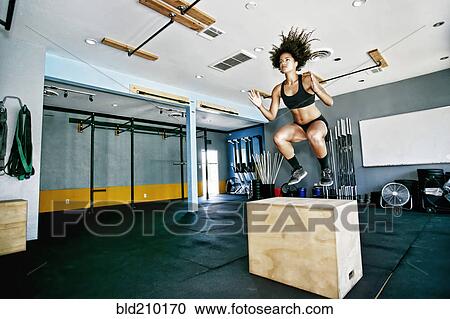 Stock Image - Mixed race woman working out in gym. Fotosearch