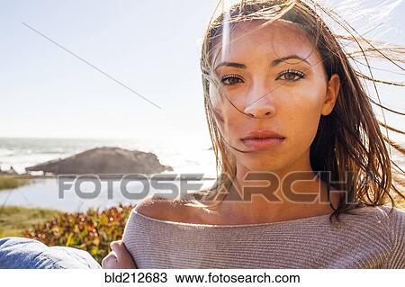 Stock Image - Mixed race woman's hair blowing in wind on coastal hillside. Fotosearch