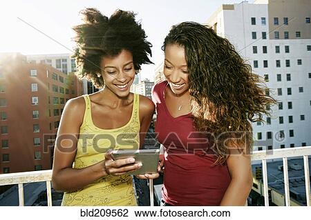 Mixed race women using digital tablet on urban rooftop View Large Photo Image Stock Image - Mixed race women using digital tablet on urban rooftop. Fotosearch