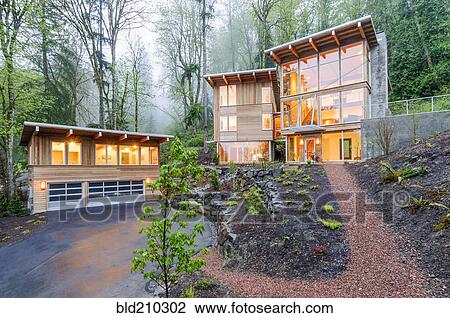Stock Image - Modern house illuminated in woods. Fotosearch