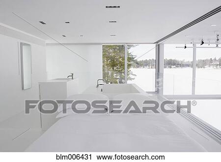 Stock Image - Modern white bedroom with tub in background. Fotosearch