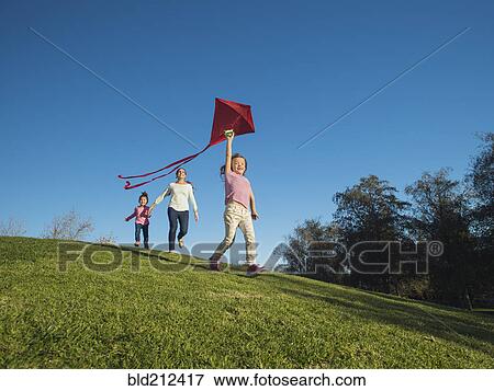 Stock Photo - Mother and children flying kite in park. Fotosearch