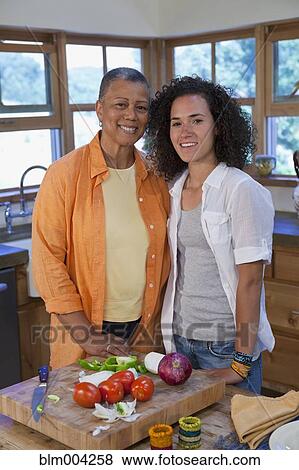 Stock Photo - Mother and daughter cutting vegetables in kitchen. Fotosearch