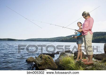 Stock Image - Mother and daughter fishing in lake. Fotosearch