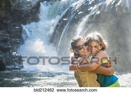Stock Image - Mother and daughter hugging by waterfall. Fotosearch