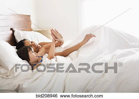 Stock Photograph - Mother and daughter laying in bed. Fotosearch