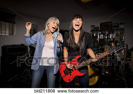 Stock Photo - Mother and daughter playing music guitar in basement. Fotosearch