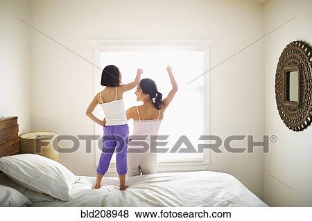 Stock Photo - Mother and daughter playing on bed. Fotosearch