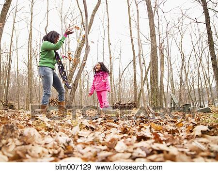 Stock Photo - Mother and daughter playing with autumn leaves. Fotosearch