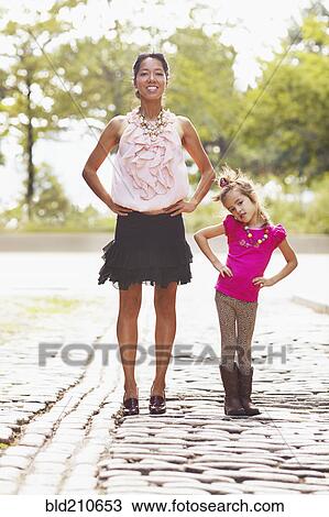 Stock Image - Mother and daughter posing on city street. Fotosearch