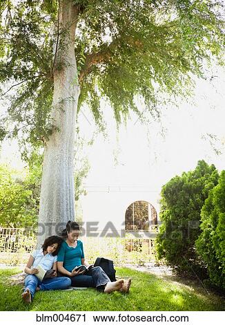 Stock Image - Mother and daughter reading in park. Fotosearch
