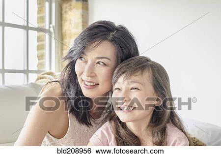 Stock Photograph - Mother and daughter smiling on sofa. Fotosearch