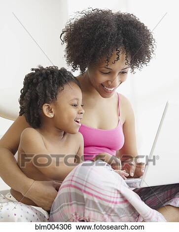 Stock Photograph - Mother and daughter using laptop. Fotosearch