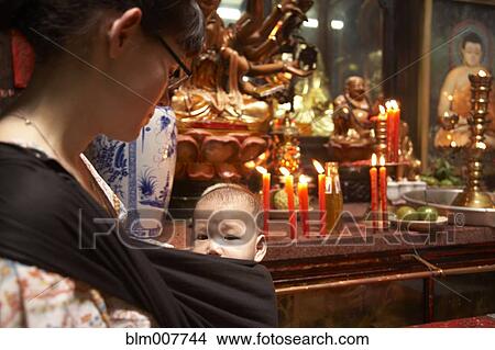 Picture - Mother carrying baby in sling in temple. Fotosearch