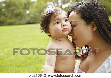 Mother cradling baby girl in park View Large Photo Image Stock Image - Mother cradling baby girl in park. Fotosearch