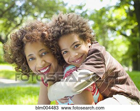 Stock Image - Mother giving son piggy back ride. Fotosearch