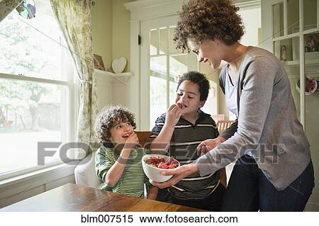 Stock Photography - Mother giving sons snack of strawberries. Fotosearch