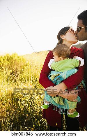 Mother holding baby and kissing husband View Large Photo Image Stock Photography - Mother holding baby and kissing husband. Fotosearch