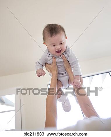 Stock Image - Mother holding baby girl overhead. Fotosearch