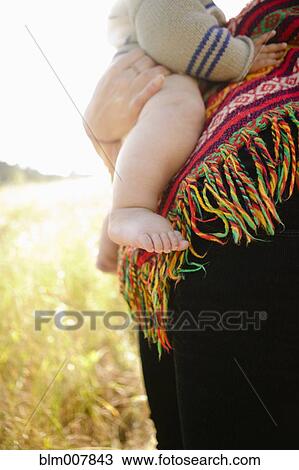 Stock Image - Mother holding baby in field. Fotosearch