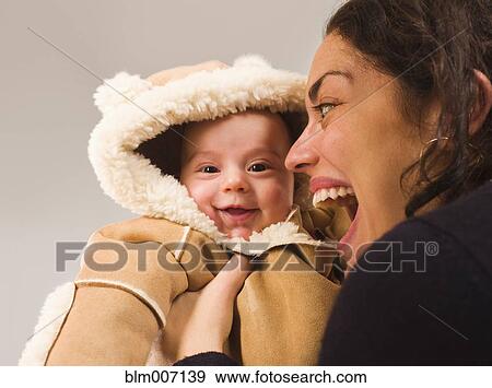 Stock Photo - Mother holding newborn baby in winter coat. Fotosearch
