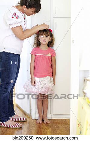 Stock Image - Mother measuring daughter's height. Fotosearch