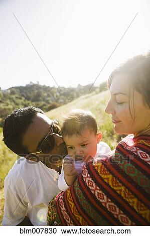 Stock Image - Mother watching father kissing baby. Fotosearch