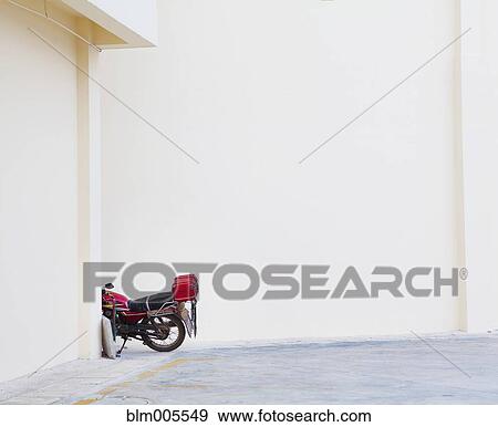 Stock Photo - Motorcycle cycle parked near white wall. Fotosearch