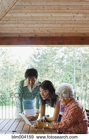Multi-generation Japanese women using laptop on patio View Large Photo Image Stock Photo - Multi-generation Japanese women using laptop on patio. Fotosearch