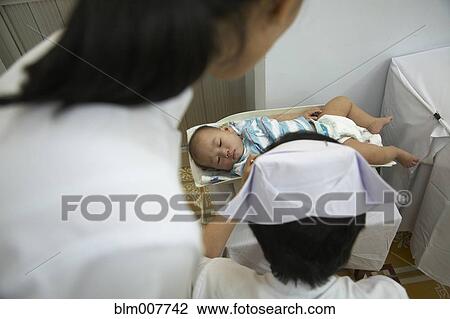 Stock Image - Nurse weighing baby in doctor's office. Fotosearch