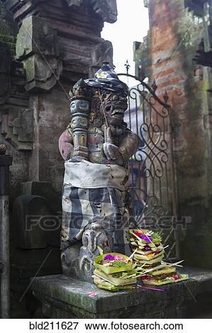 Stock Photo - Offerings at base of Hindu statue, Ubud, Bali, Indonesia. Fotosearch