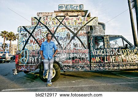 Stock Photo - Older Black woman standing by decorated truck. Fotosearch