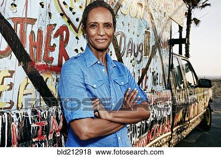 Stock Photo - Older Black woman standing by decorated truck. Fotosearch