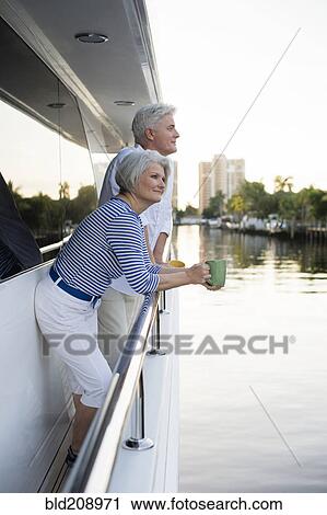Stock Image - Older Caucasian couple having coffee on boat deck. Fotosearch