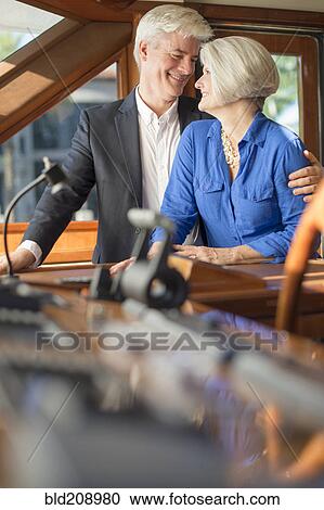 Stock Image - Older Caucasian couple hugging on yacht. Fotosearch