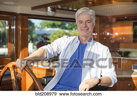 Stock Photo - Older Caucasian man steering yacht. Fotosearch