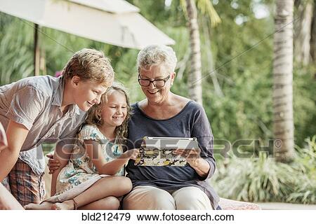 Older Caucasian woman and grandchildren looking at photo album View Large Photo Image Stock Photo - Older Caucasian woman and grandchildren looking at photo album. Fotosearch
