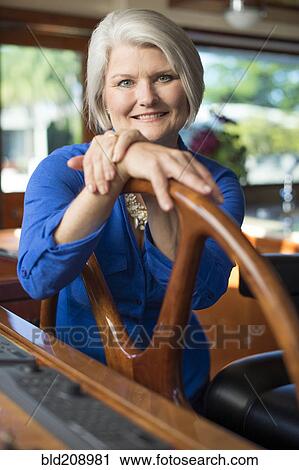 Stock Image - Older Caucasian woman steering yacht. Fotosearch